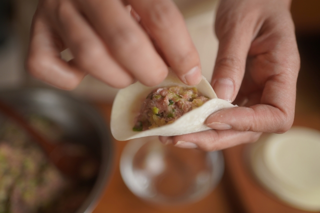 餃子の皮を手で包む